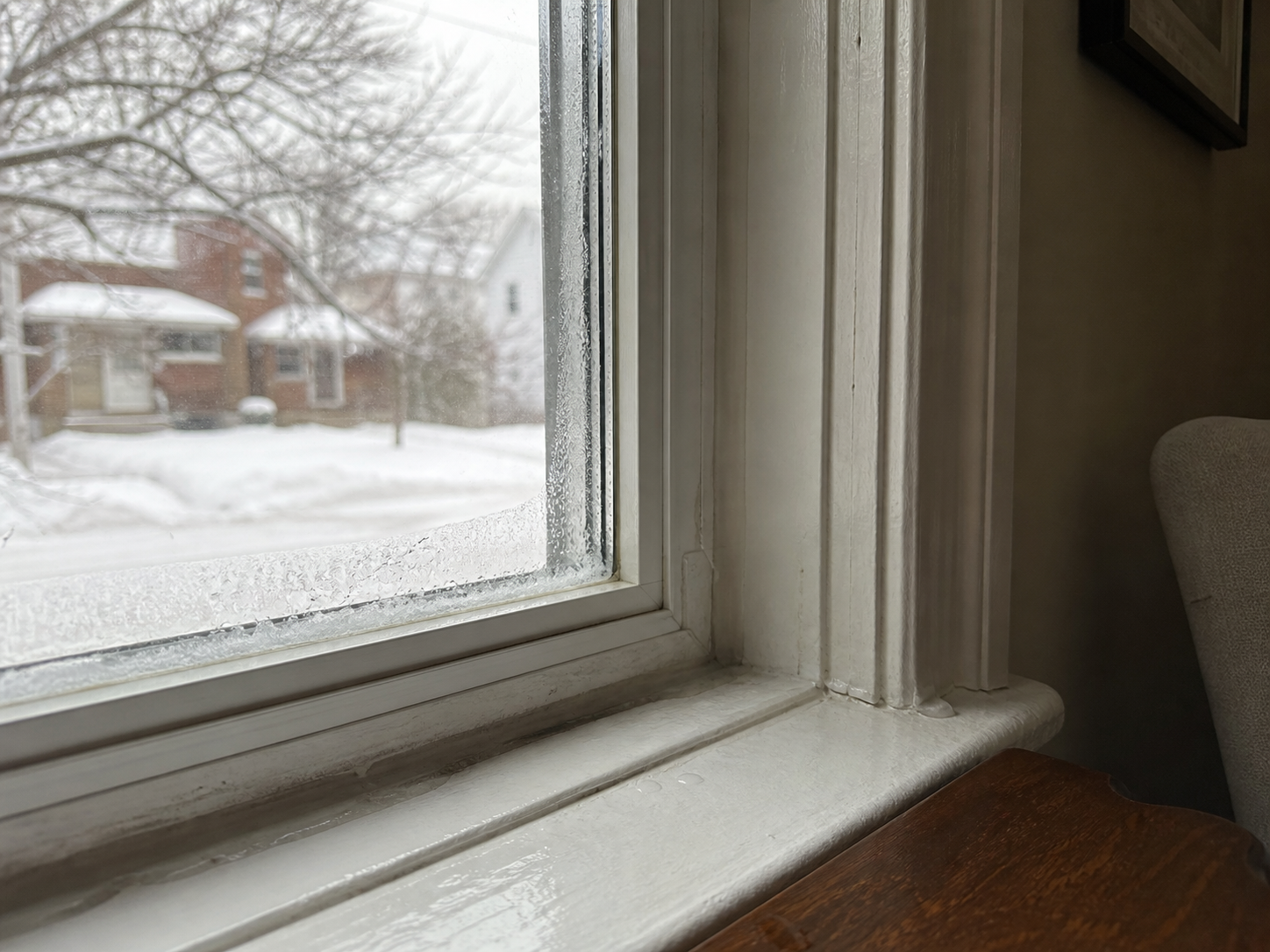 Interior window sill with winter condensation and light ice buildup in a Canadian house