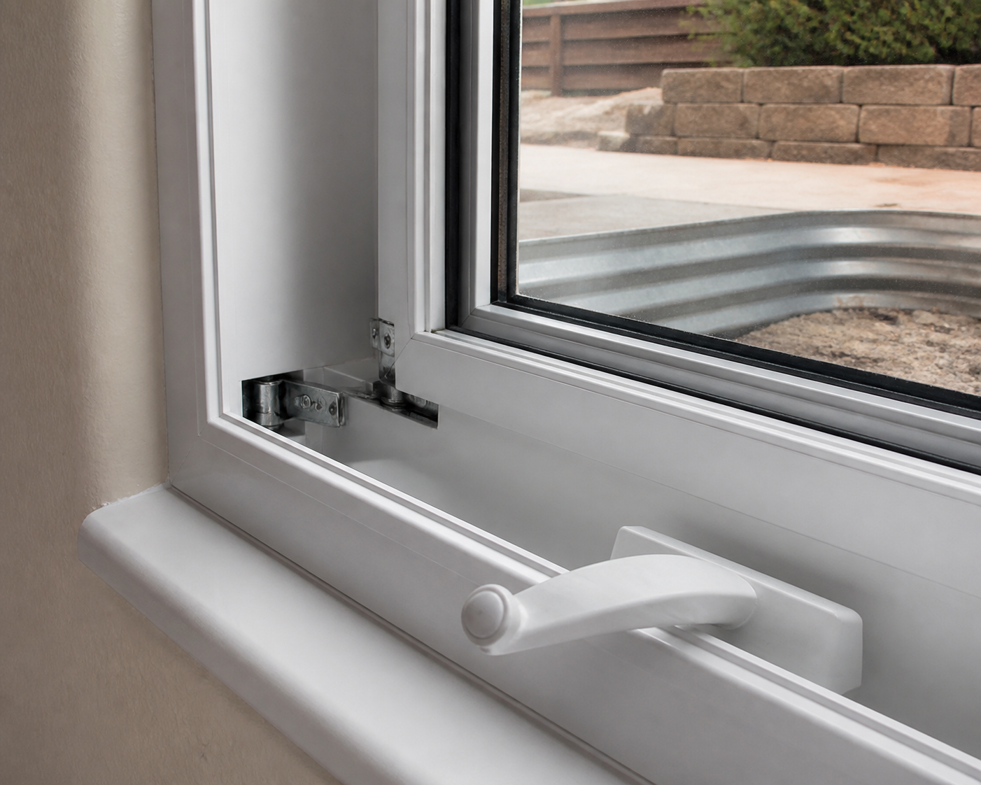 Close-up of a casement window crank and locking hardware on a vinyl frame