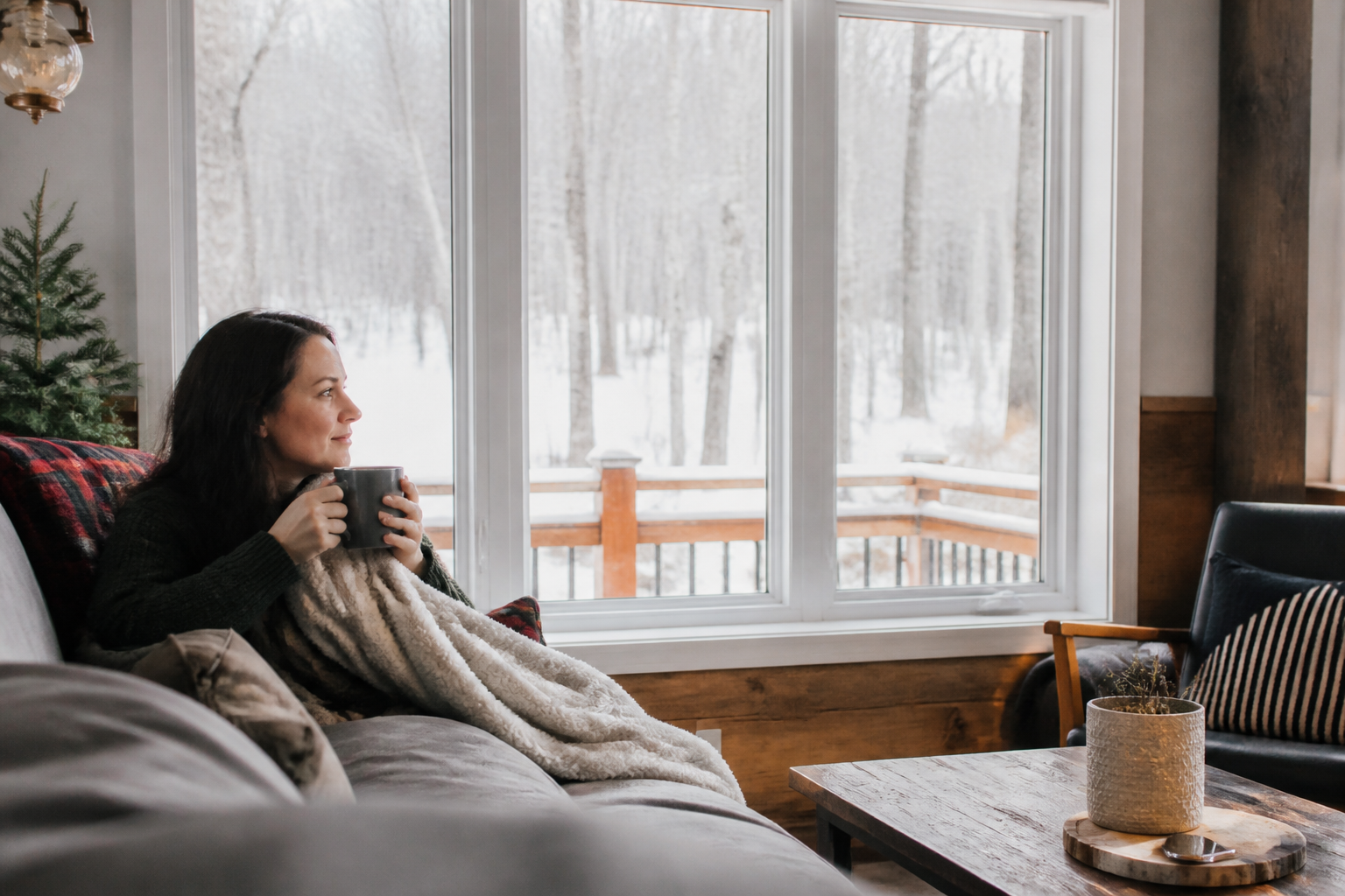Cozy Ontario living room in winter with large vinyl windows, soft daylight, snow visible outside, and warm interior seating near the glass