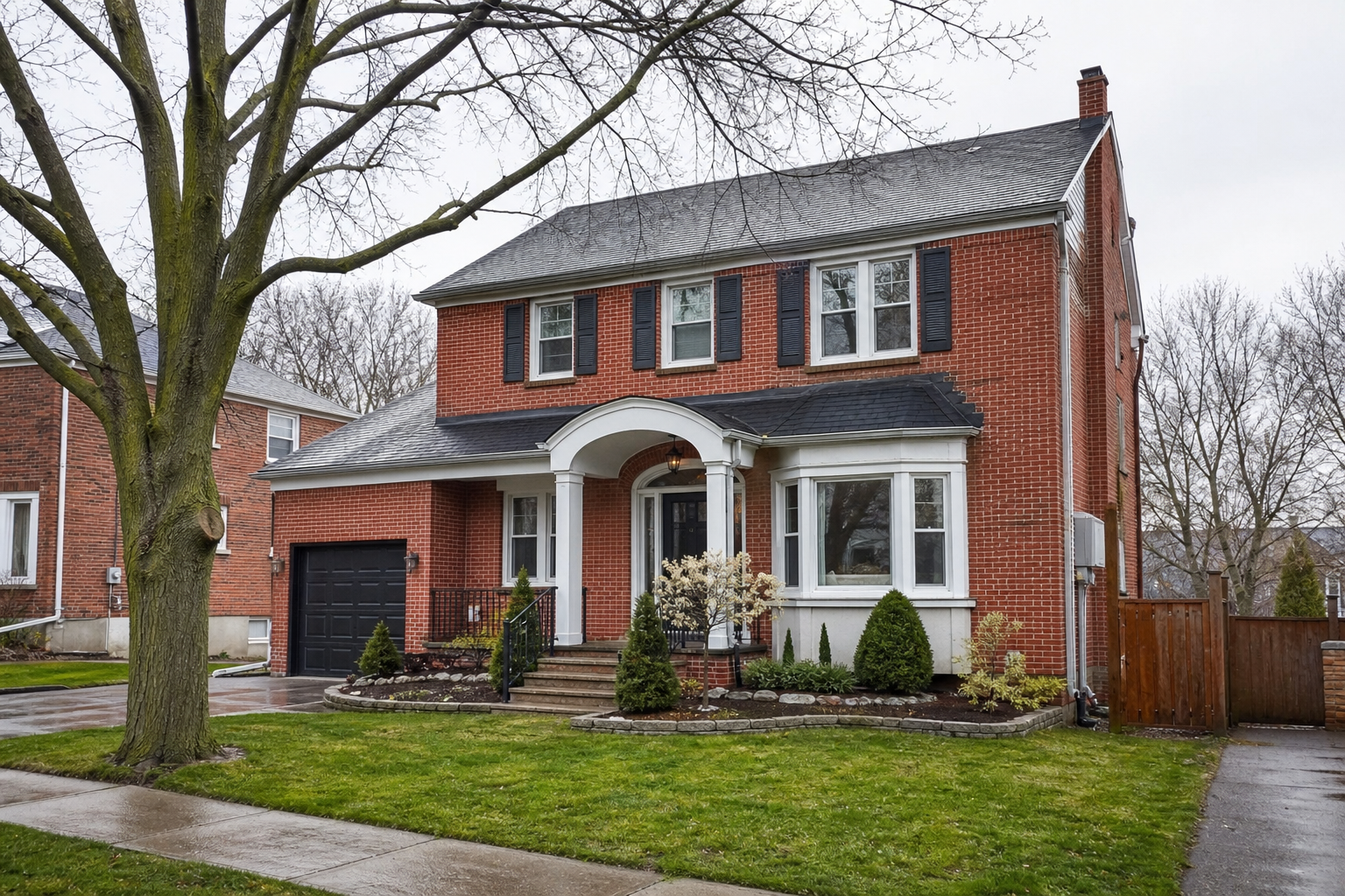 Classic Ontario brick two-storey home with large front windows on an overcast day